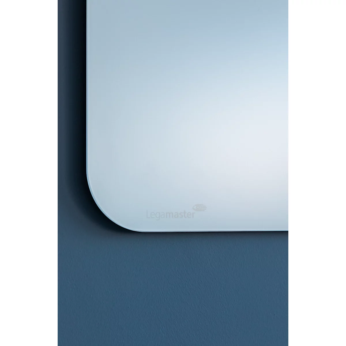 Gros plan sur un miroir rectangulaire aux coins arrondis. Le texte "Legamaster" est visible sur la surface. L'arrière-plan est bleu.