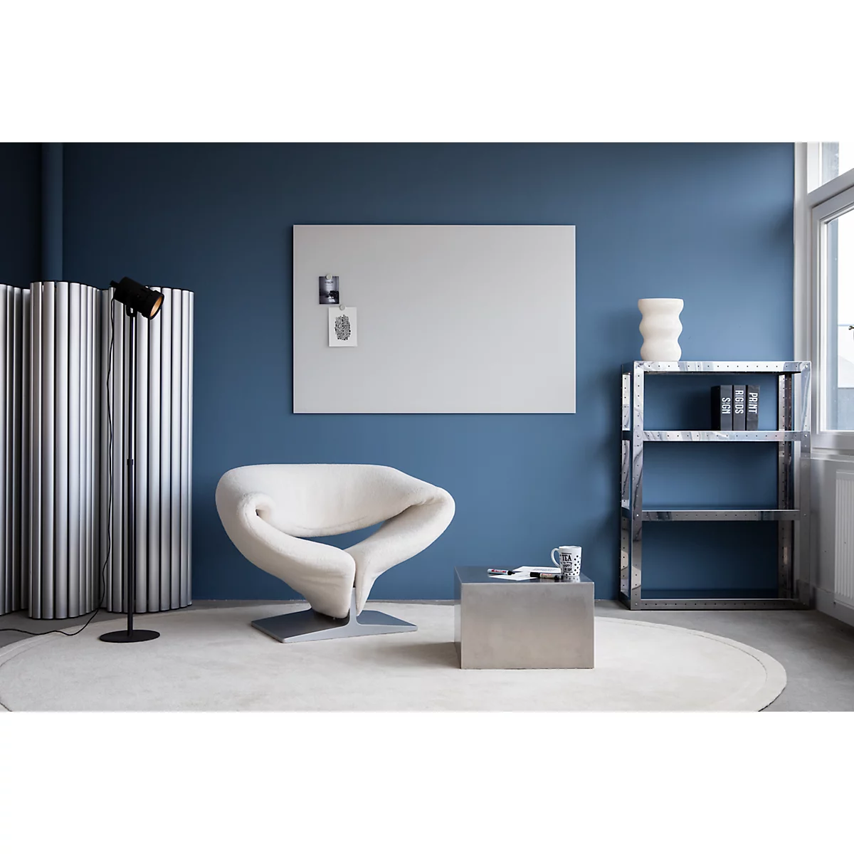 Un salon élégant avec un fauteuil blanc, un tableau blanc et une étagère en métal.