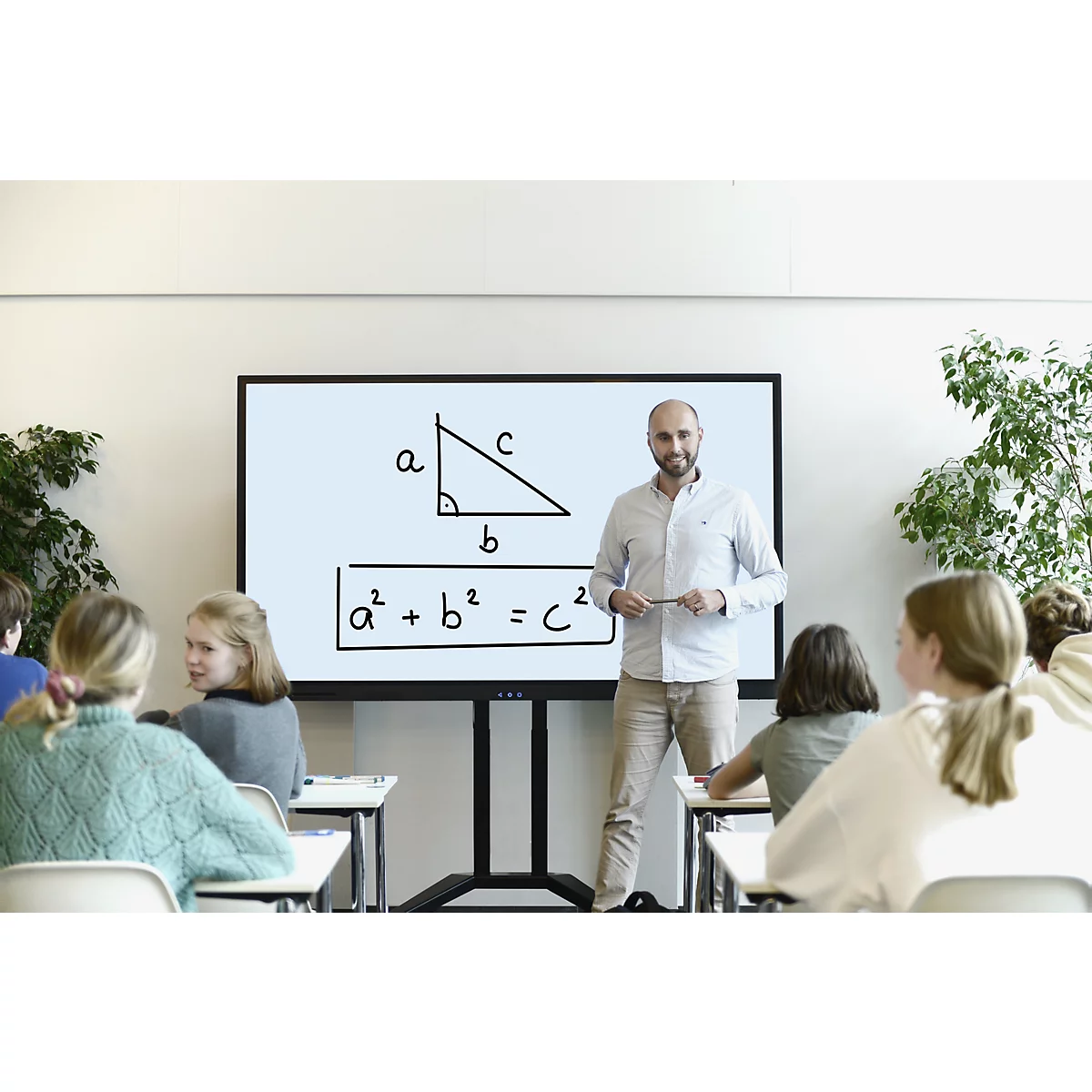 Ein Lehrer erklärt in einem Klassenzimmer die Mathematikformel a² + b² = c². Schüler sitzen an Tischen.