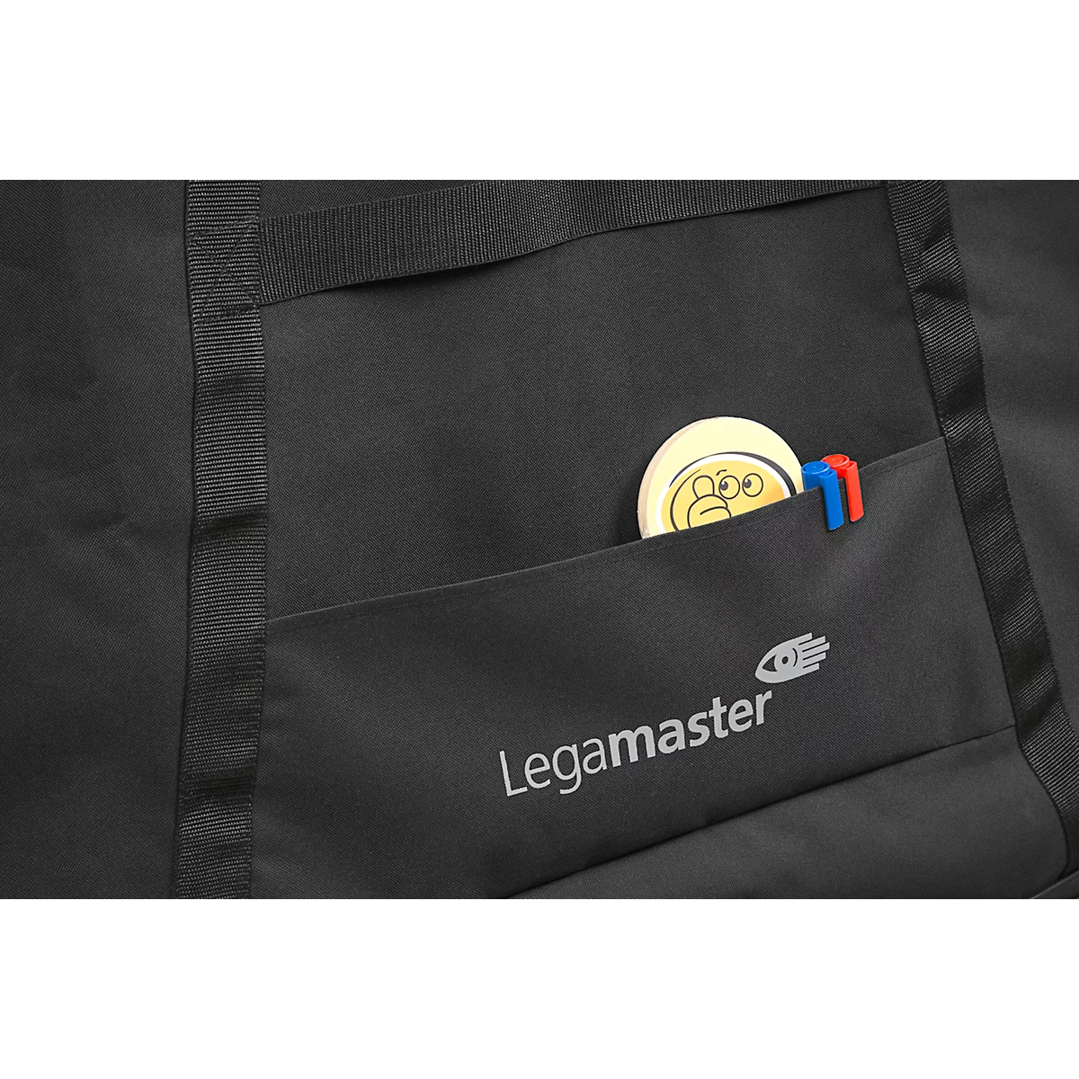 Close-up of a black bag with a pocket. A round yellow object with a face is in the pocket.