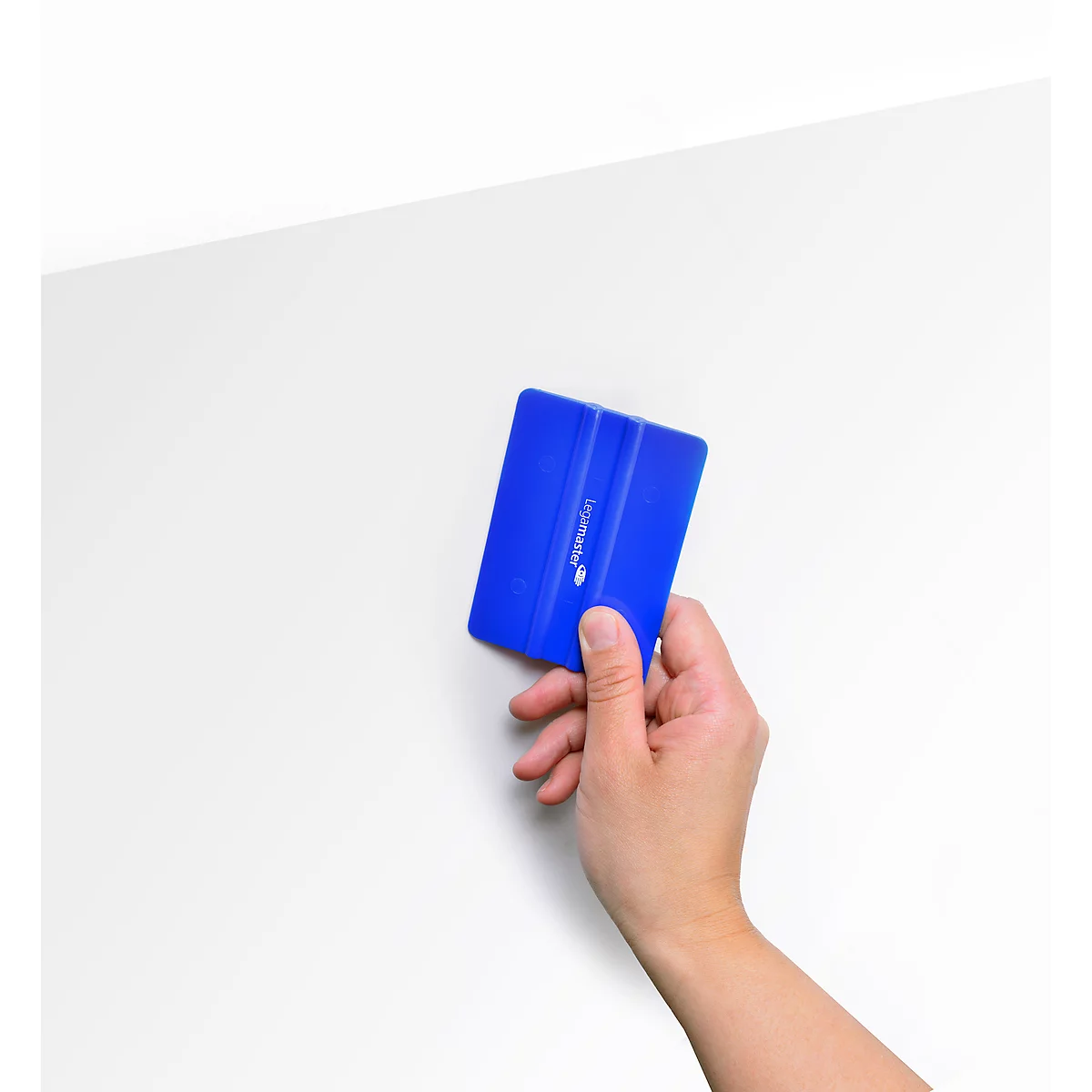 Hand holding a blue squeegee against a white background.