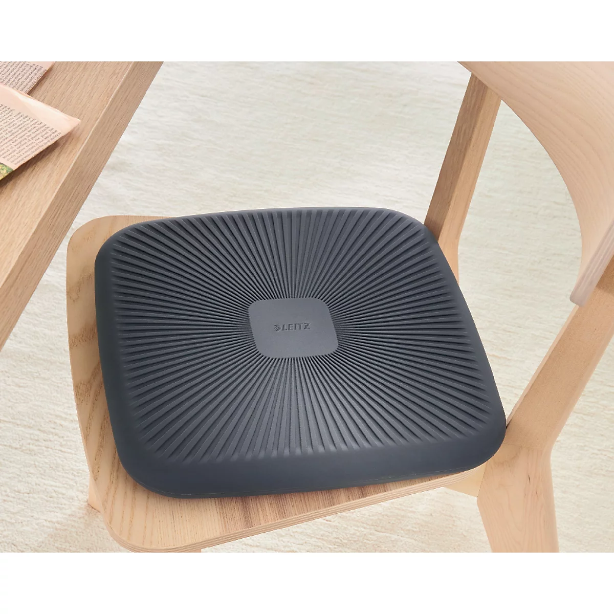 Coussin de siège ergonomique gris foncé sur une chaise en bois, prix de design 2024.