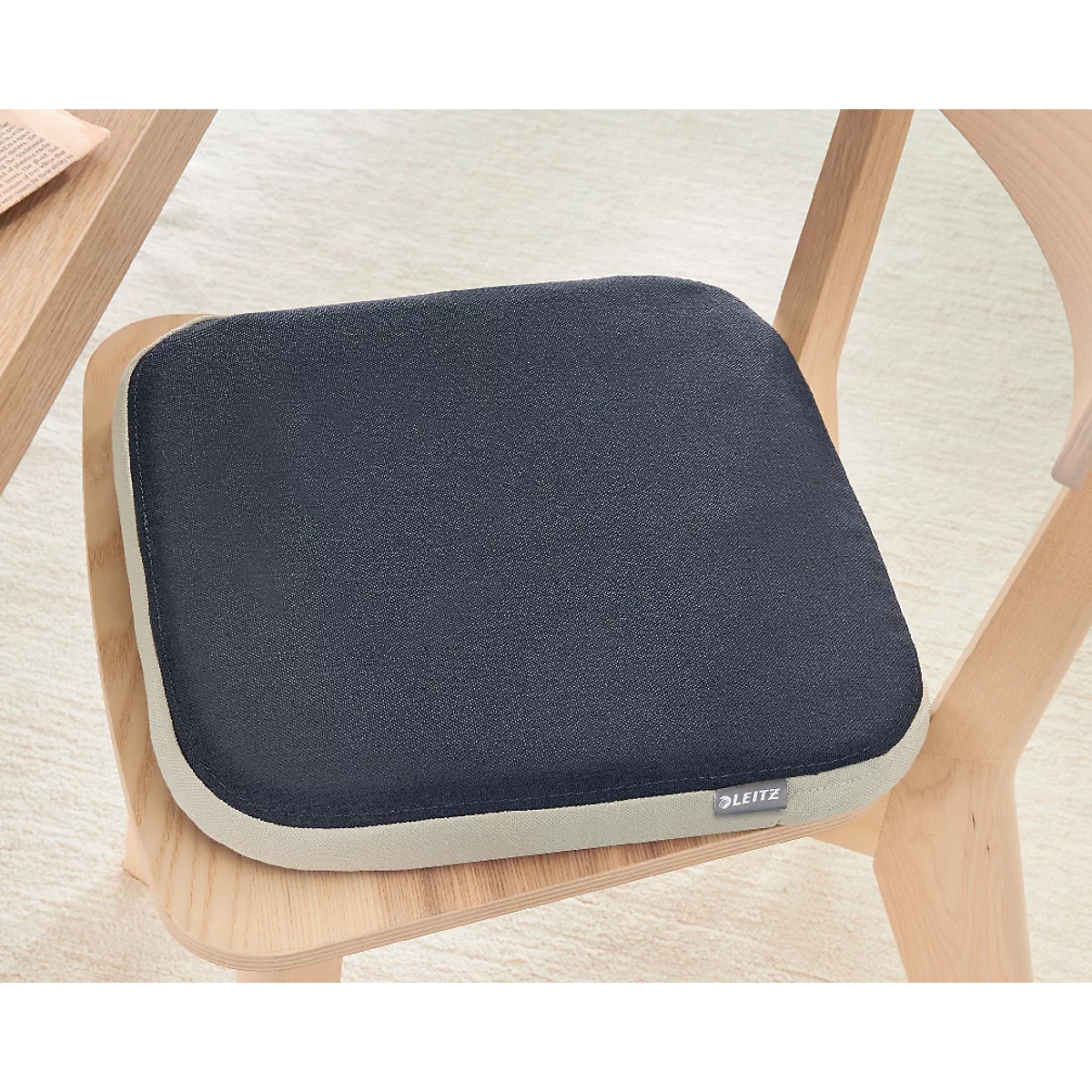 Un coussin de siège bleu foncé sur une chaise en bois. Des logos et du texte de récompense sont visibles en bas.