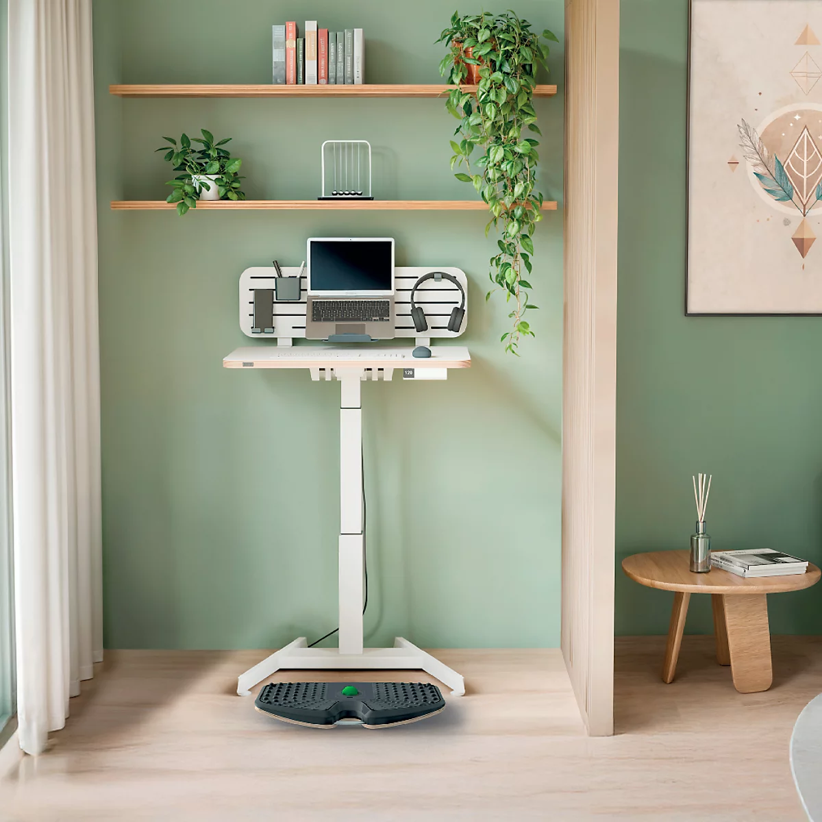 Un bureau blanc réglable en hauteur avec un ordinateur portable et des accessoires, devant une étagère avec des plantes.