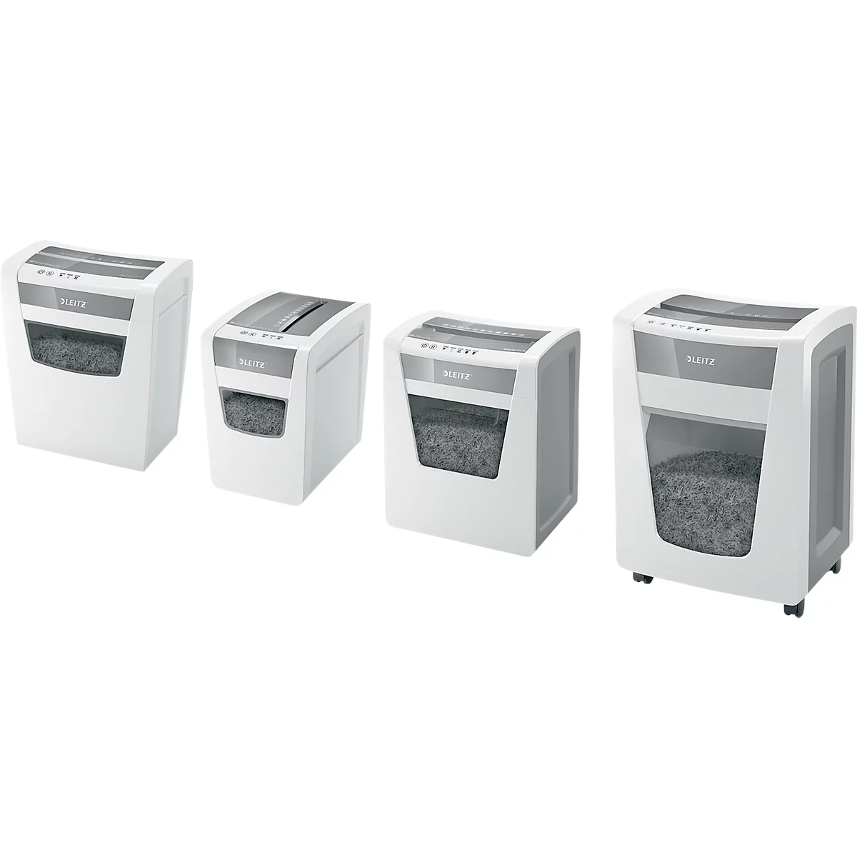 Four white paper shredders side by side. Paper shreds are visible through transparent windows. Gray controls.