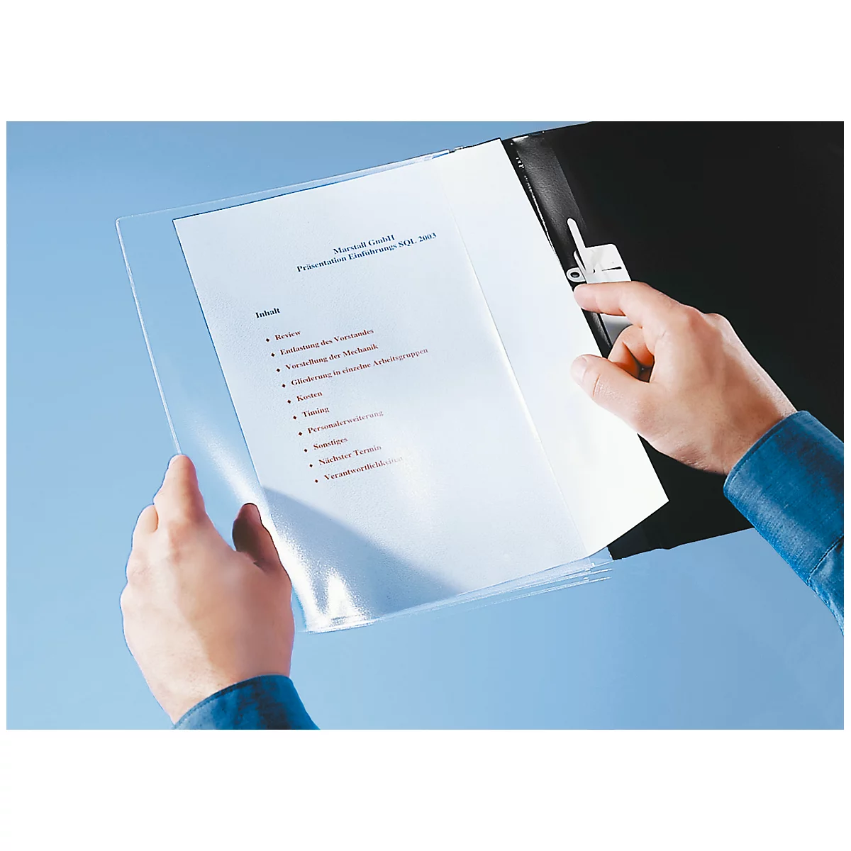 Two hands holding a transparent sheet protector with documents. The background is light blue.