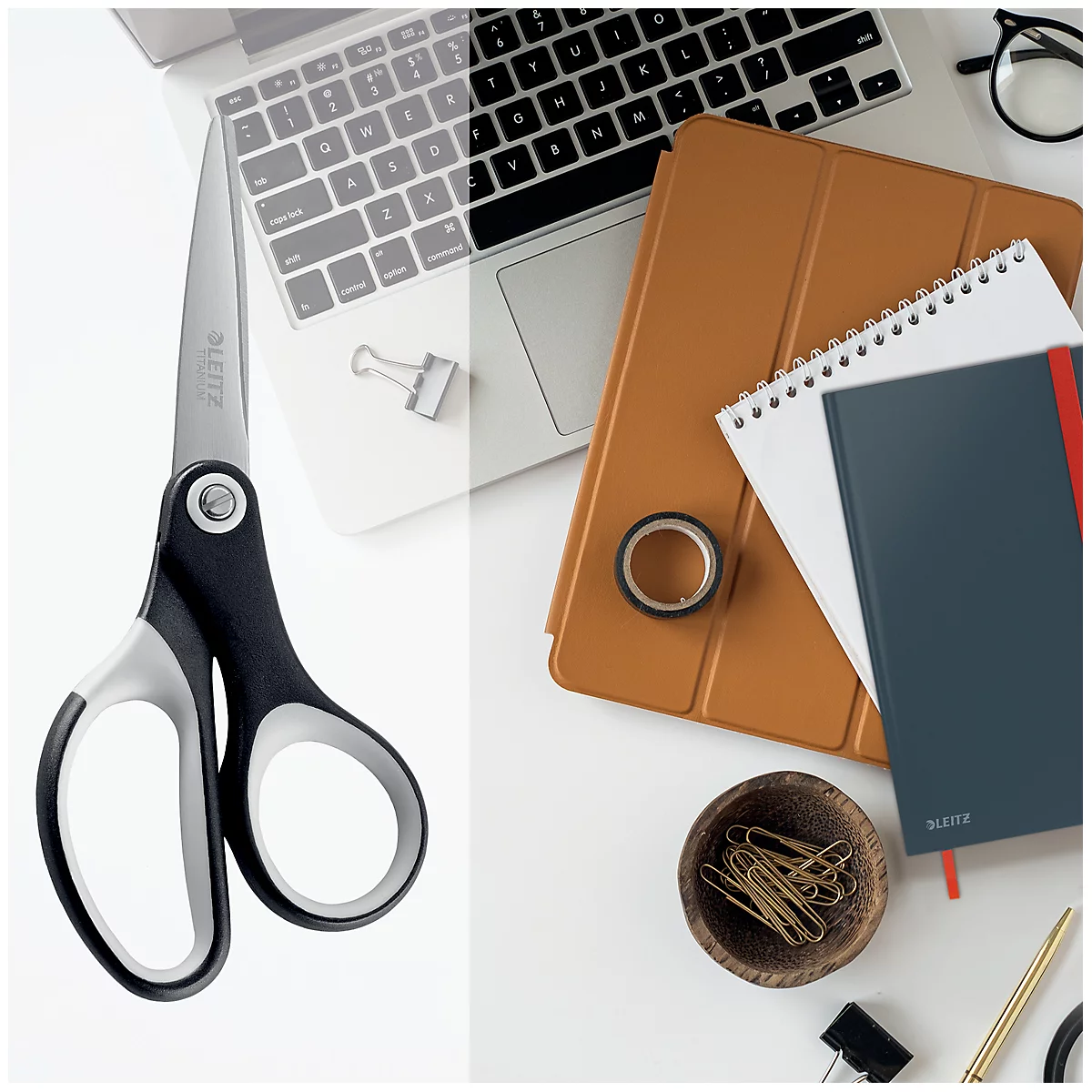 Schere, Notizbuch, Stift, Klebeband und Laptop auf weißem Untergrund.