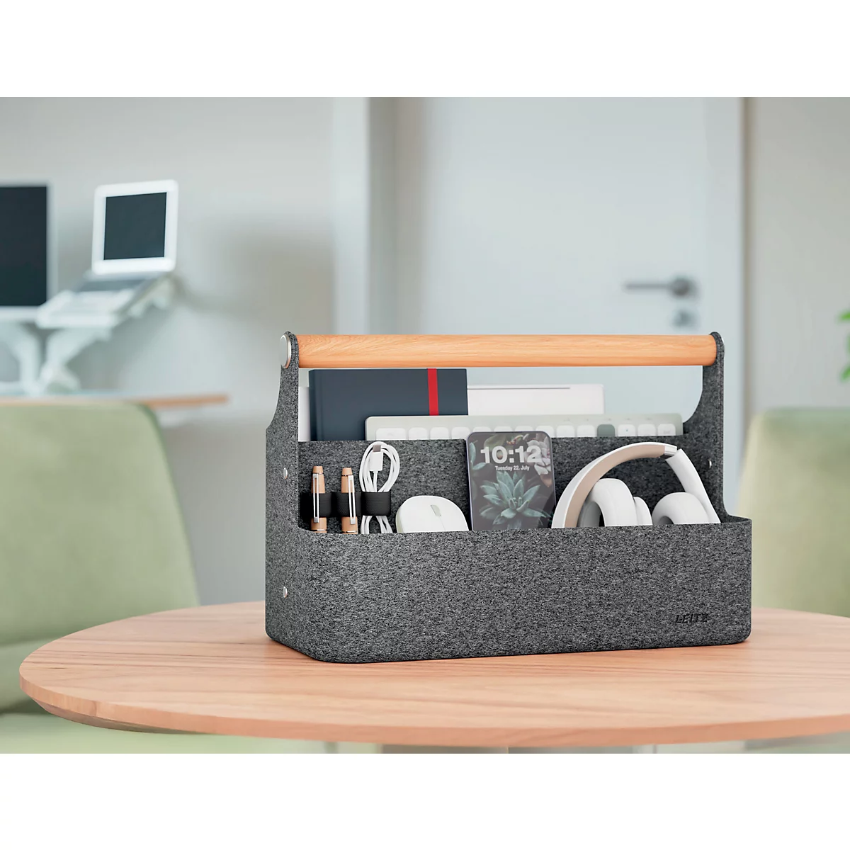 Person stellt einen grauen Filz-Organizer mit Tablet auf einen hellen Schreibtisch.