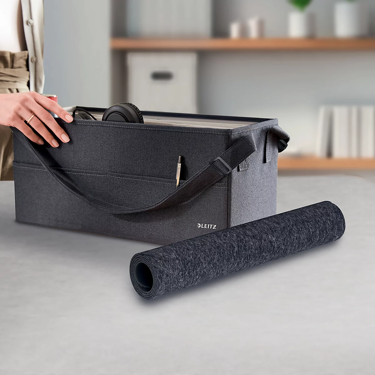 Dunkelgraue Aufbewahrungsbox mit Inhalt und gerollter Matte.