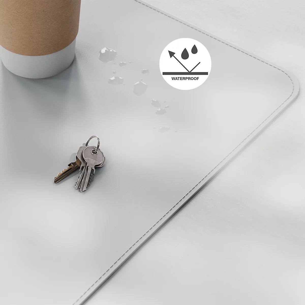 Tapis de bureau gris clair, taches d'eau, clés et tasse à café. Logo "Waterproof".