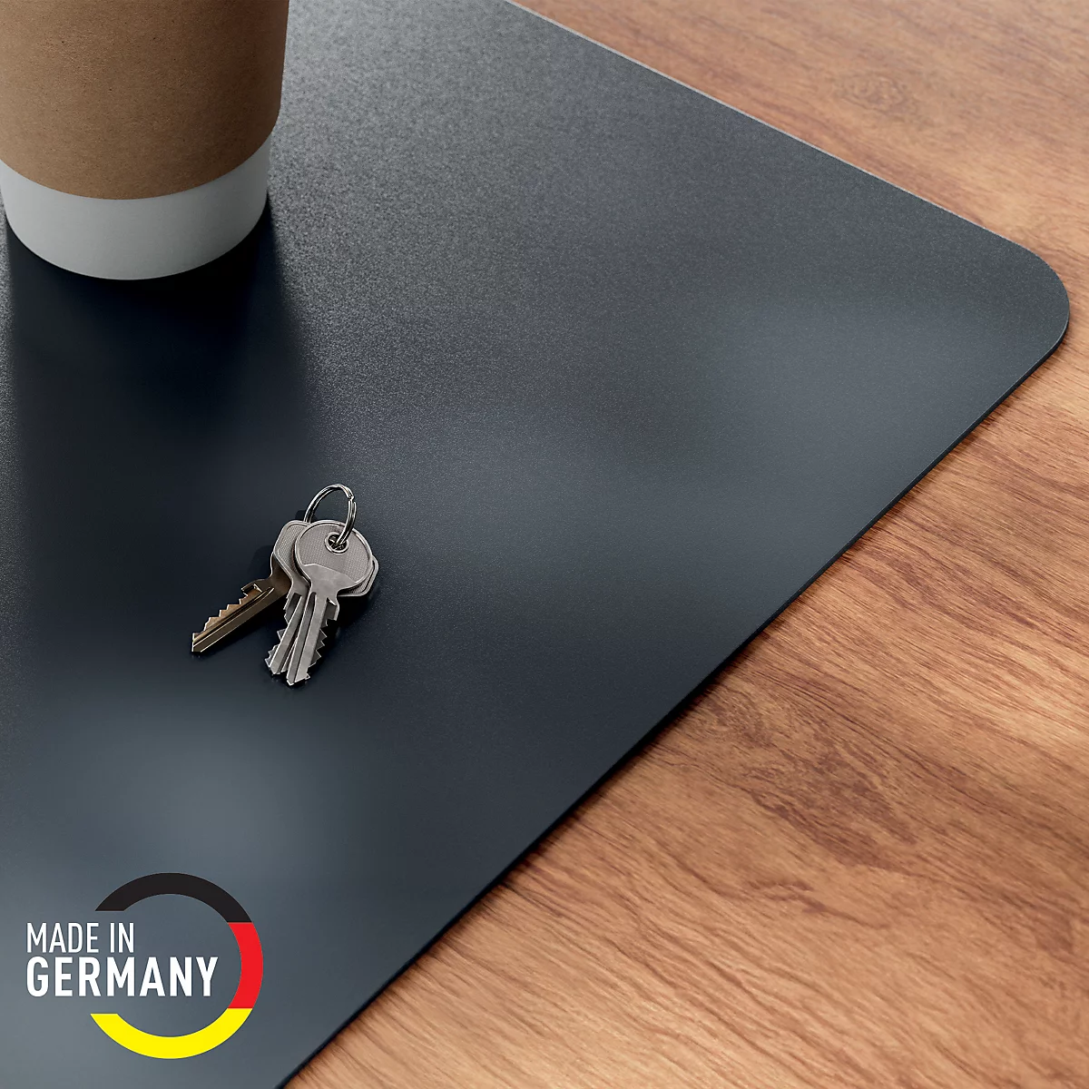 Tapis de bureau gris foncé avec coins arrondis, clés et tasse à café. Impression "Made in Germany".