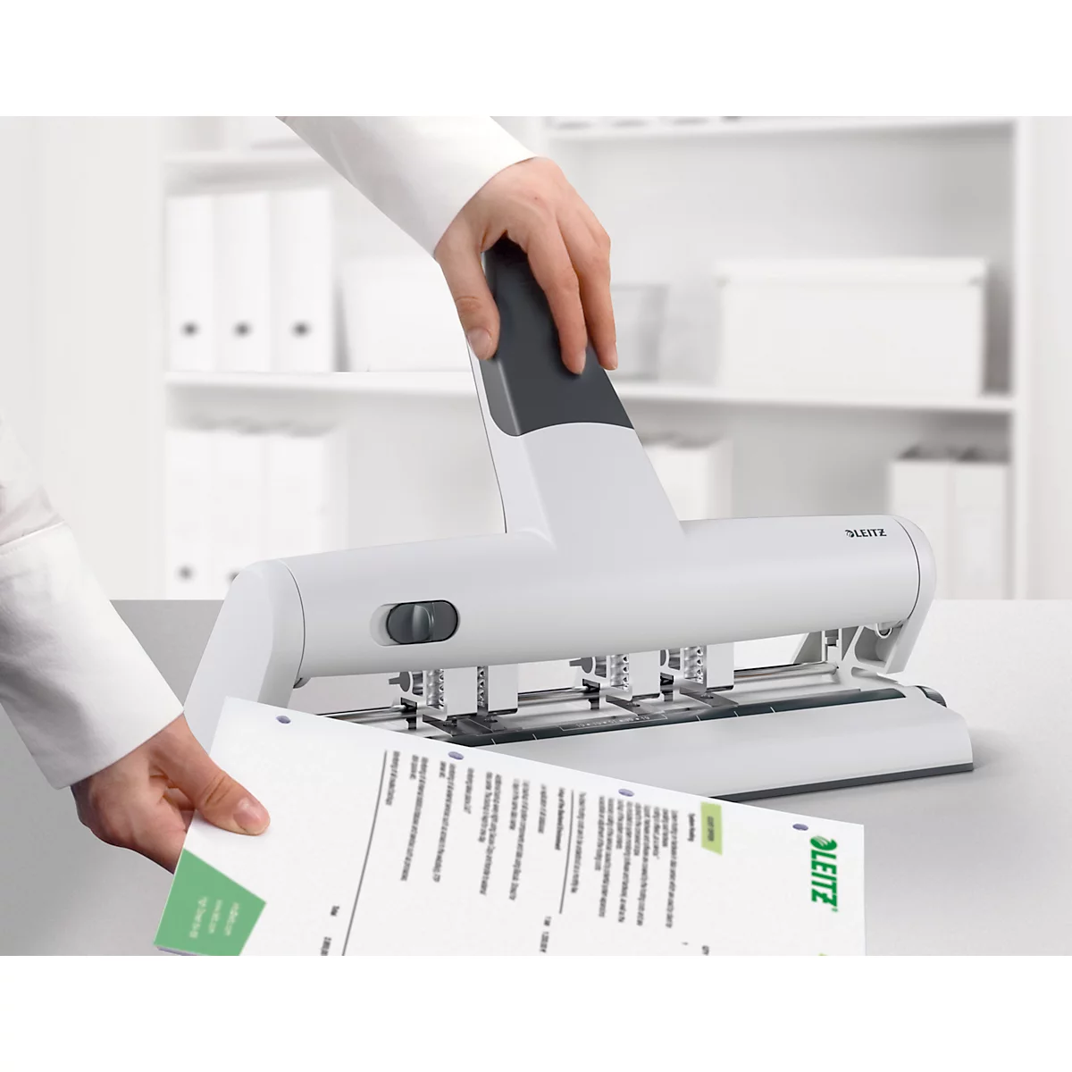 Person punching paper with a white Leitz punch.
