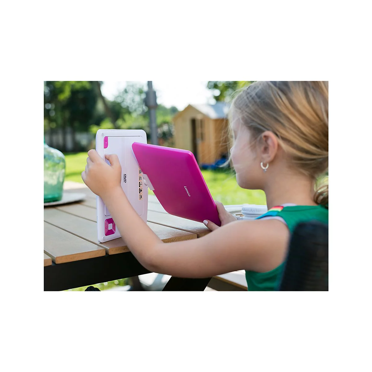 Ein blondes MÃ¤dchen hÃ¤lt ein pinkes Tablet an einem Tisch im Garten. Es scheint das Tablet zu befestigen oder zu lÃ¶sen.