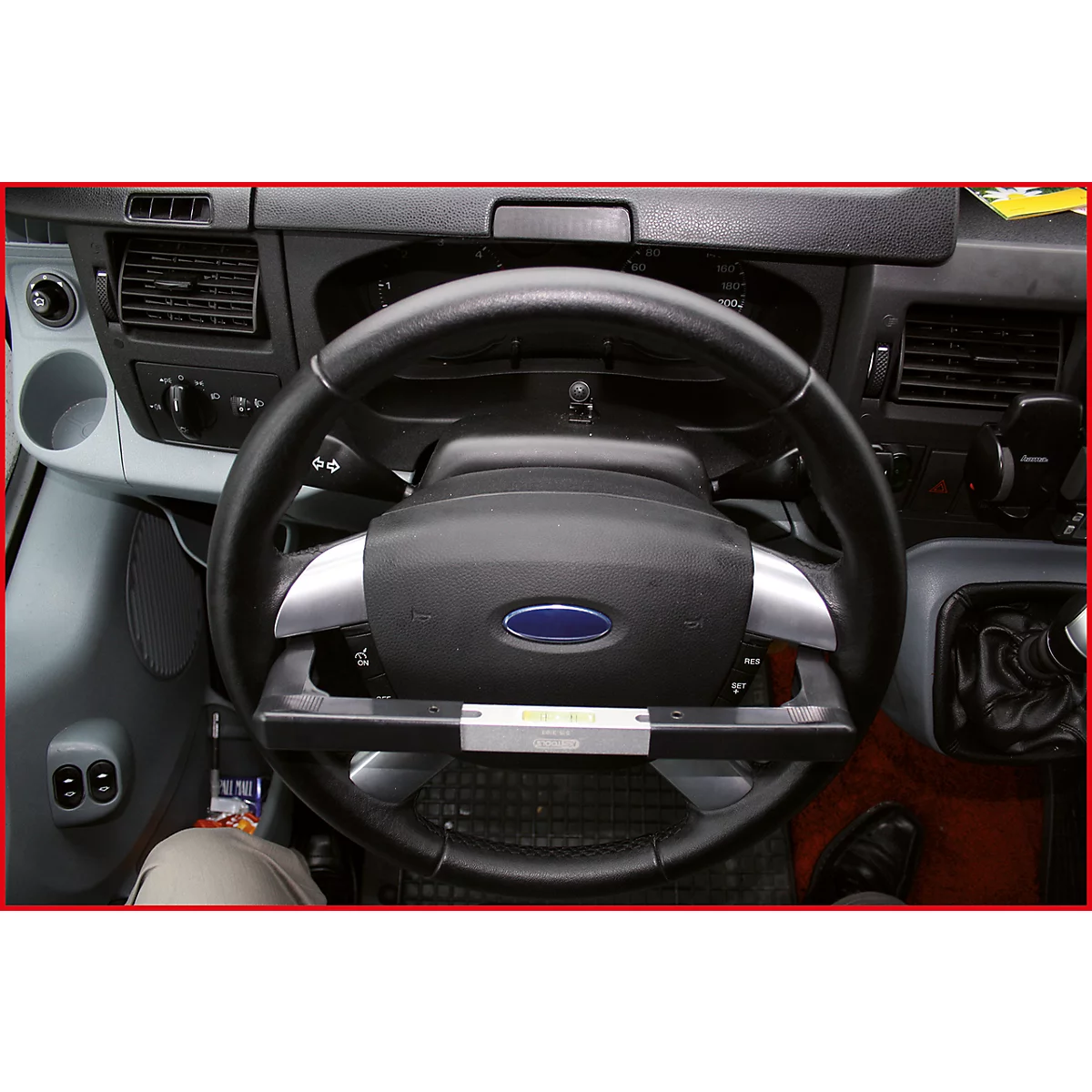 Nahaufnahme des Lenkrads eines Ford-Transporters, mit dem blauen Ford-Logo. Das Lenkrad hat ein zusätzliches Bedienelement.