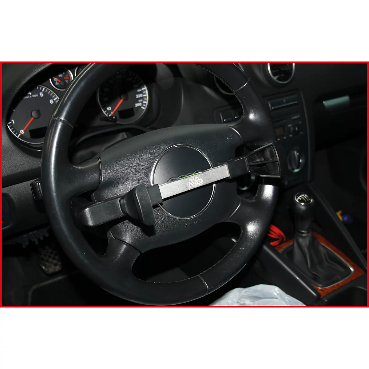 Lenkrad eines Autos mit montierter Diebstahlsicherung. Das Schloss ist silberfarben und befindet sich mittig.