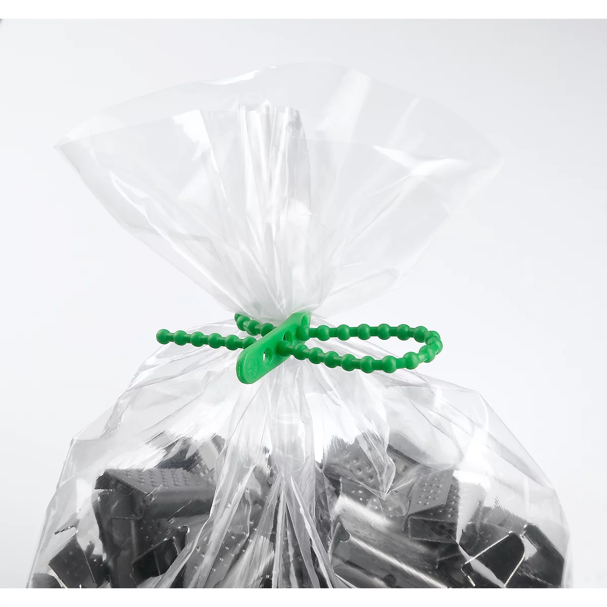 A transparent plastic bag, closed with a green cord closure. The bag contains dark objects that are not further identifiable.