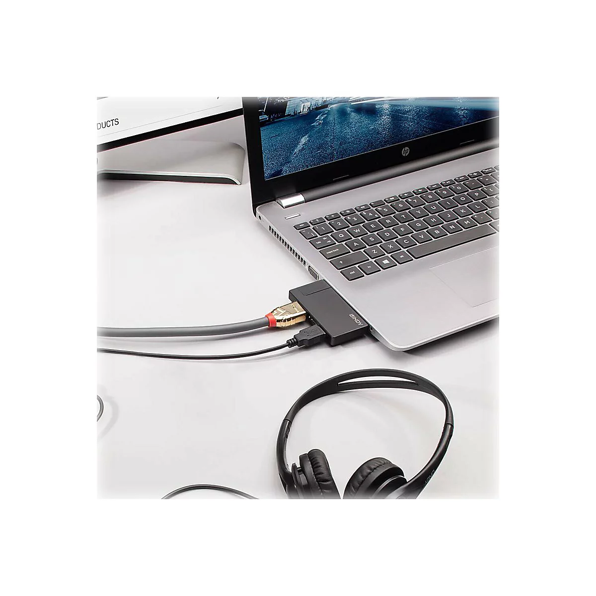 Ein Laptop mit angeschlossenen Kabeln und KopfhÃ¶rern. Ein Adapter verbindet das Notebook mit einem Monitor.
