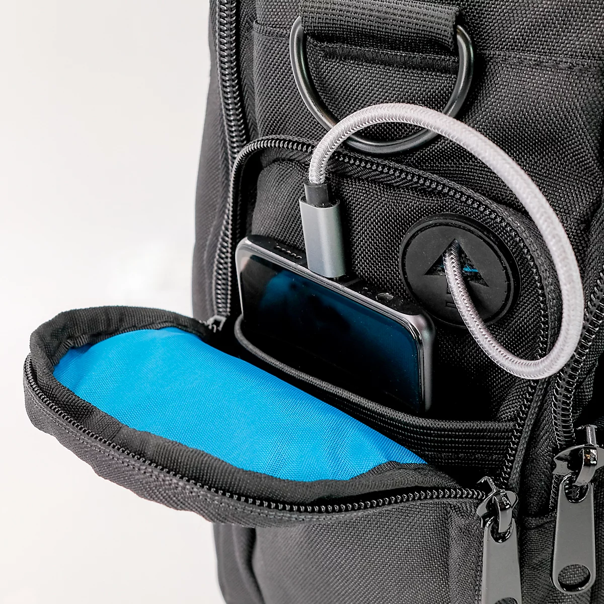 Sac noir avec intérieur bleu et smartphone avec câble de chargement.
