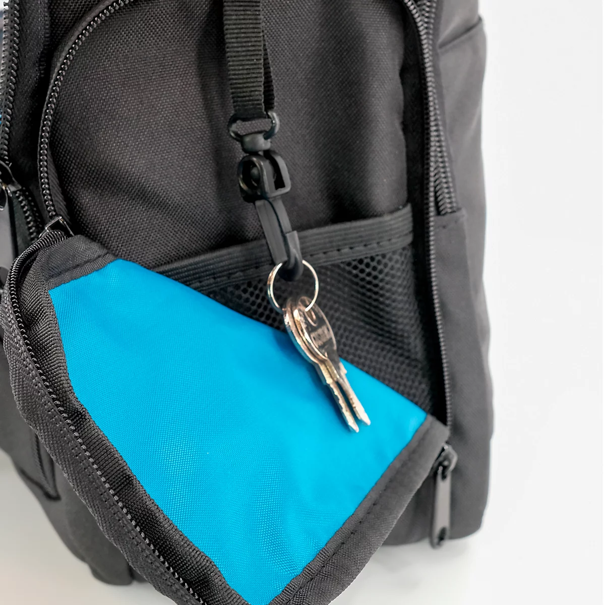 Detailaufnahme einer schwarzen Tasche mit einer hellblauen Geldbörse und Schlüsseln.
