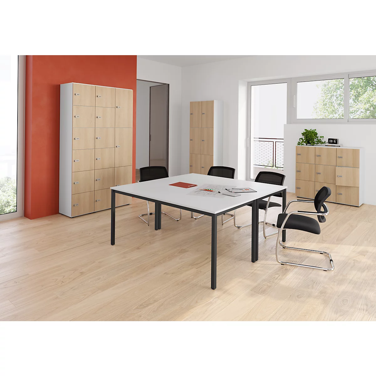 Kantoor met tafel, stoelen en kasten in licht hout. De tafel is bedekt met papieren en een rood boek.