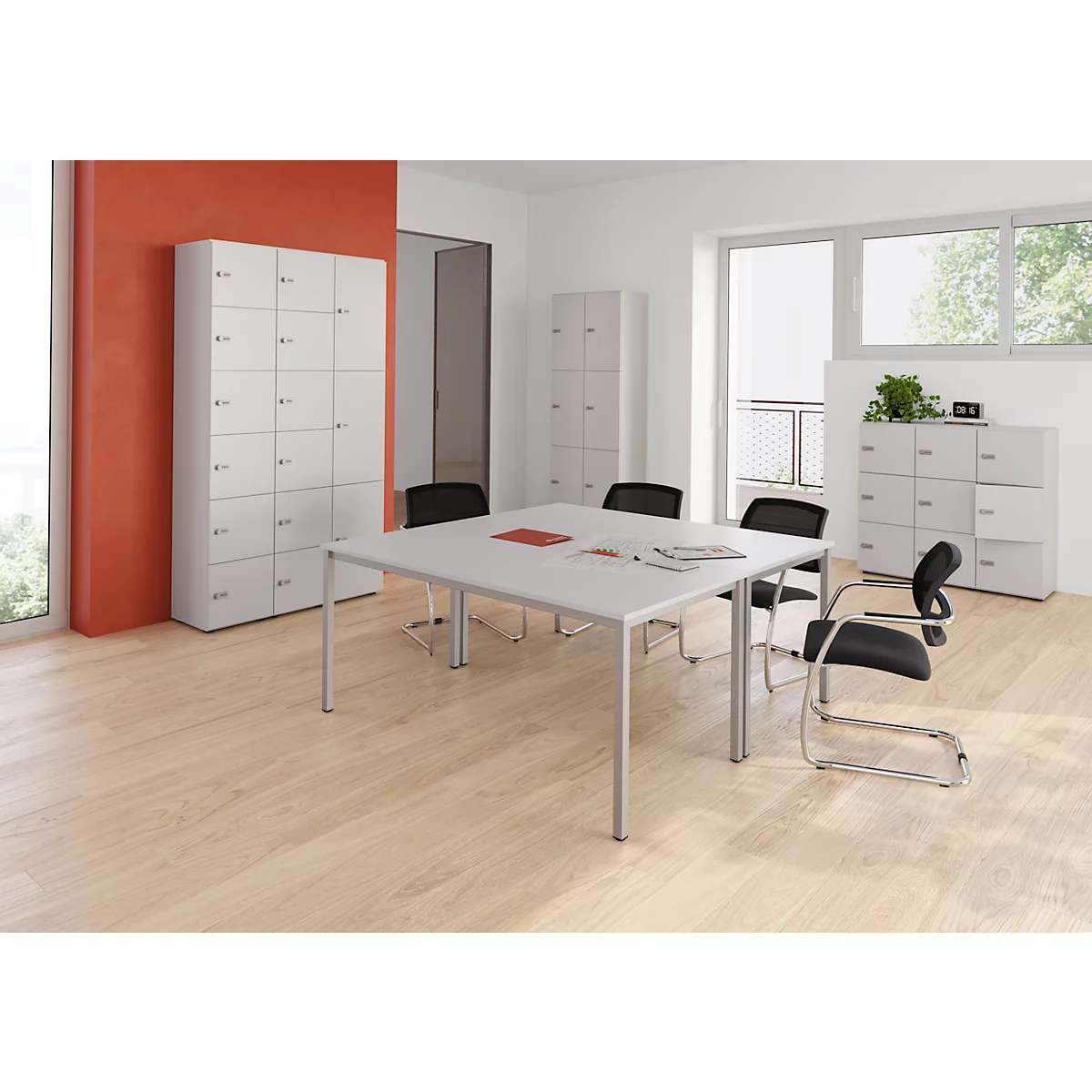 Een kantoor met lichte houten vloeren, witte tafel, zwarte stoelen en kasten. Een rode accentmuur.