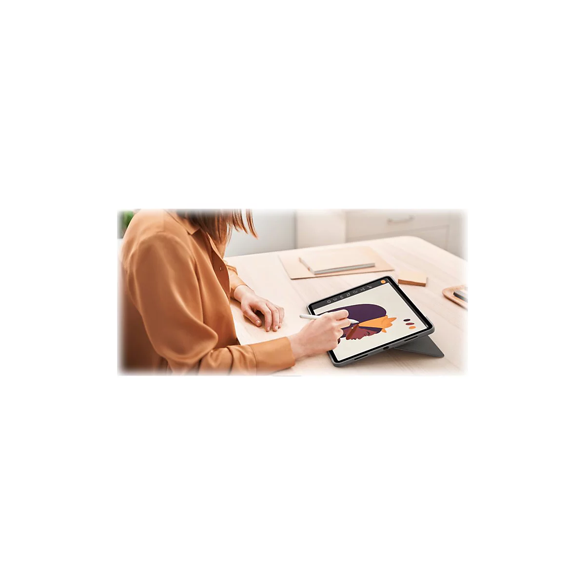 Person zeichnet mit Stift auf Tablet. Auf dem Tisch liegen weitere Notizen.