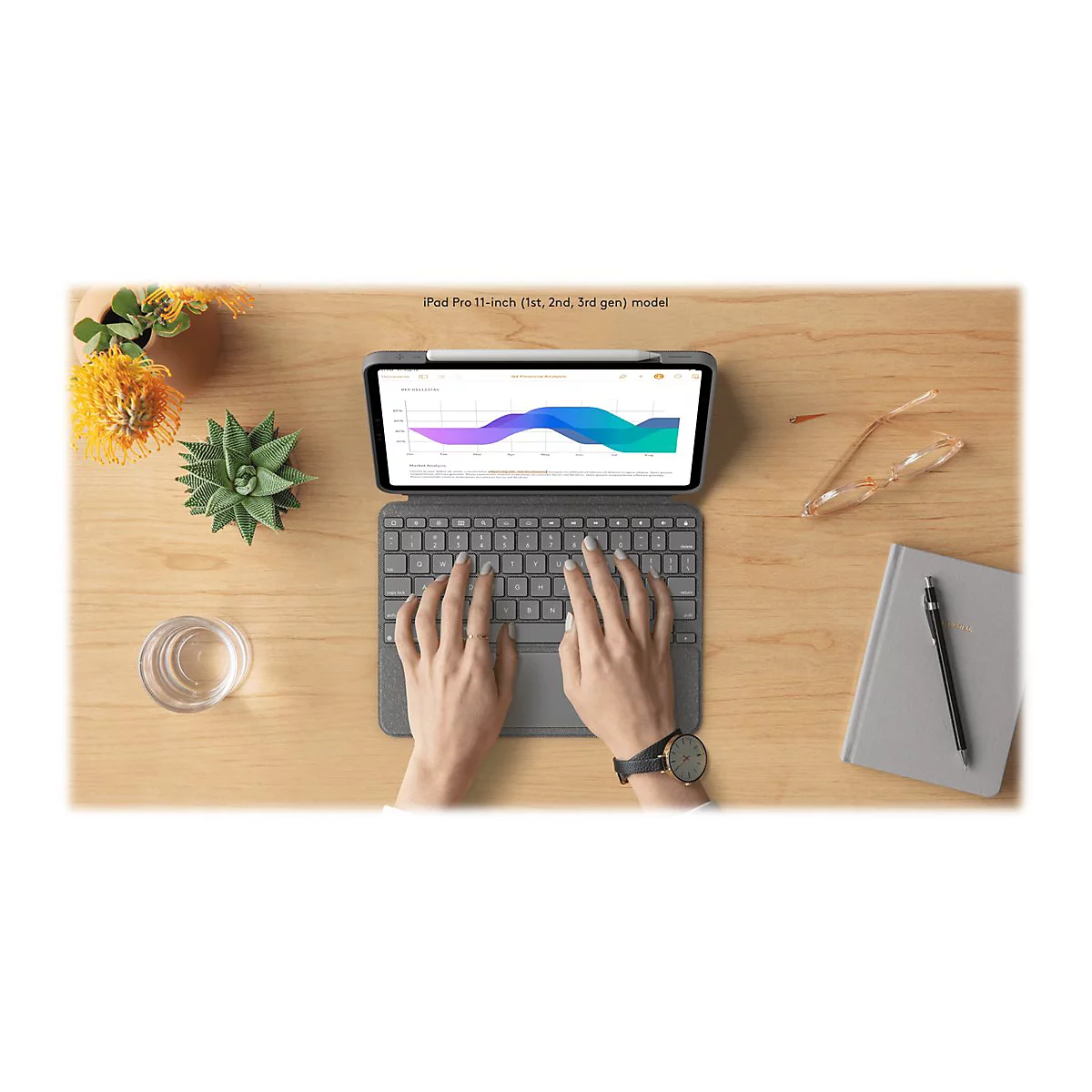 Eine Person tippt auf einem Tablet mit angeschlossenem Keyboard auf einem Holztisch. Auf dem Bildschirm ist ein Diagramm zu sehen.
