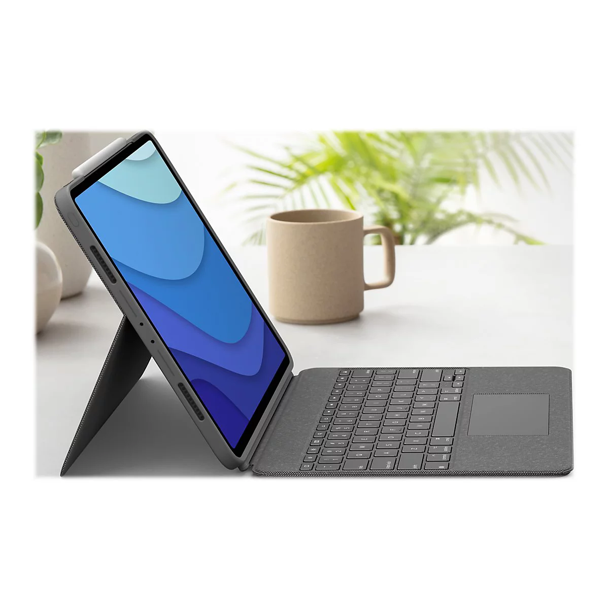 Ein graues Tablet mit aufgestellter Hülle und Tastatur. Auf dem Bildschirm ist eine blaue Grafik zu sehen, daneben eine Kaffeetasse.