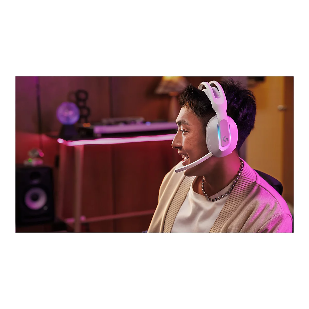Junger Mann mit Headset, lächelnd. Der Hintergrund ist rosa beleuchtet.