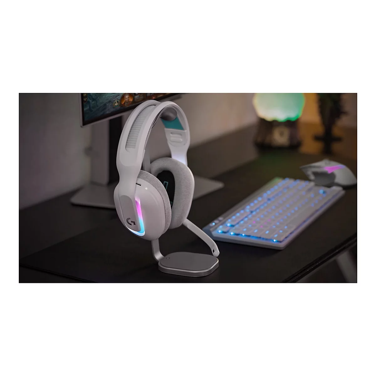 Weißes Gaming-Headset mit LED-Beleuchtung steht auf einem Tisch neben Tastatur und Maus.