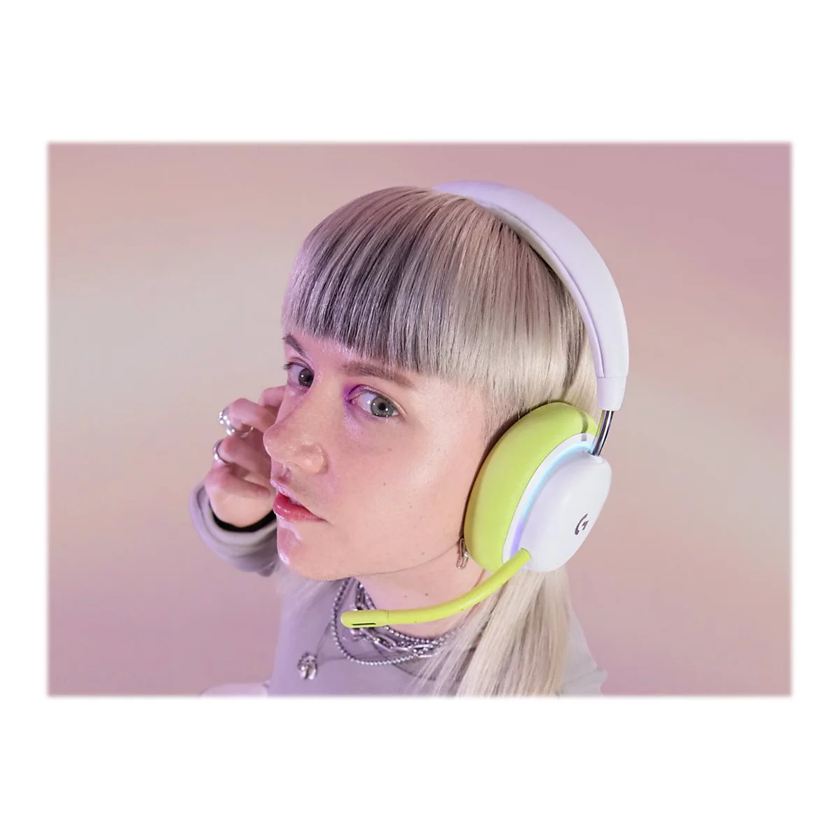 Junge Frau mit hellem Haar und Headset mit Mikrofon. Hintergrund in Rosa- und LilatÃ¶nen.