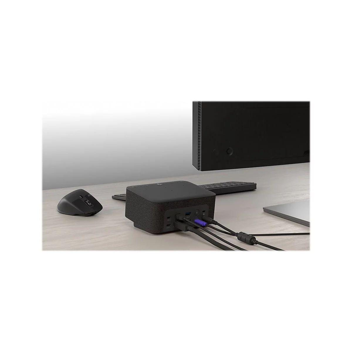 Schwarzer Hub mit Kabeln an einem Schreibtisch. Maus, Monitor und Laptop im Hintergrund. Details sind gut zu sehen.