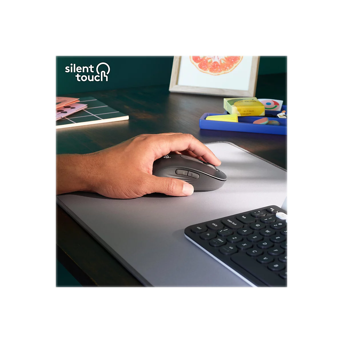 Une main utilise une souris d'ordinateur grise sur un tapis de souris gris. Une partie d'un clavier est visible.