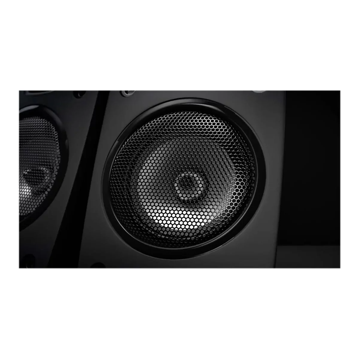 Gros plan sur un haut-parleur noir avec une grille métallique. L'accent est mis sur le grand haut-parleur rond avec une grille en nid d'abeille.