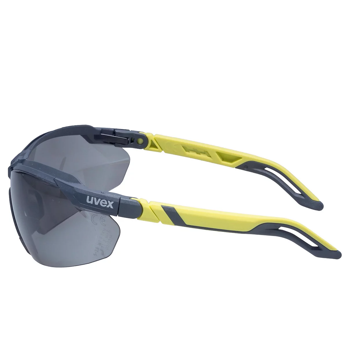 Lunettes de sécurité grises et jaunes, vues de côté. Les verres sont teintés foncés, la monture grise, les branches jaunes avec des accents gris.