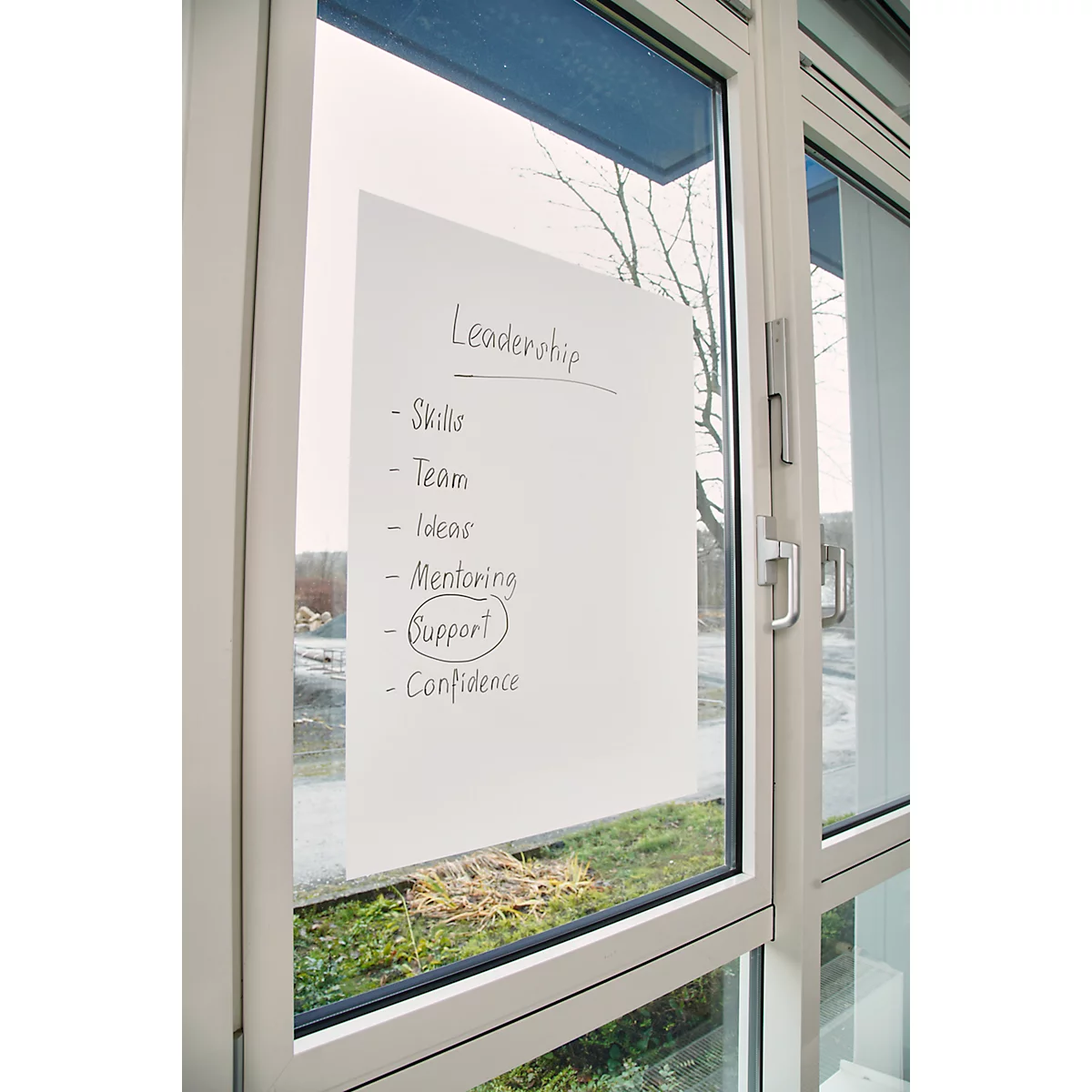 Ein Blatt Papier mit einer handgeschriebenen Liste mit dem Titel „Leadership“, durch ein Fenster aufgenommen. Der Begriff „Support“ ist eingekreist.