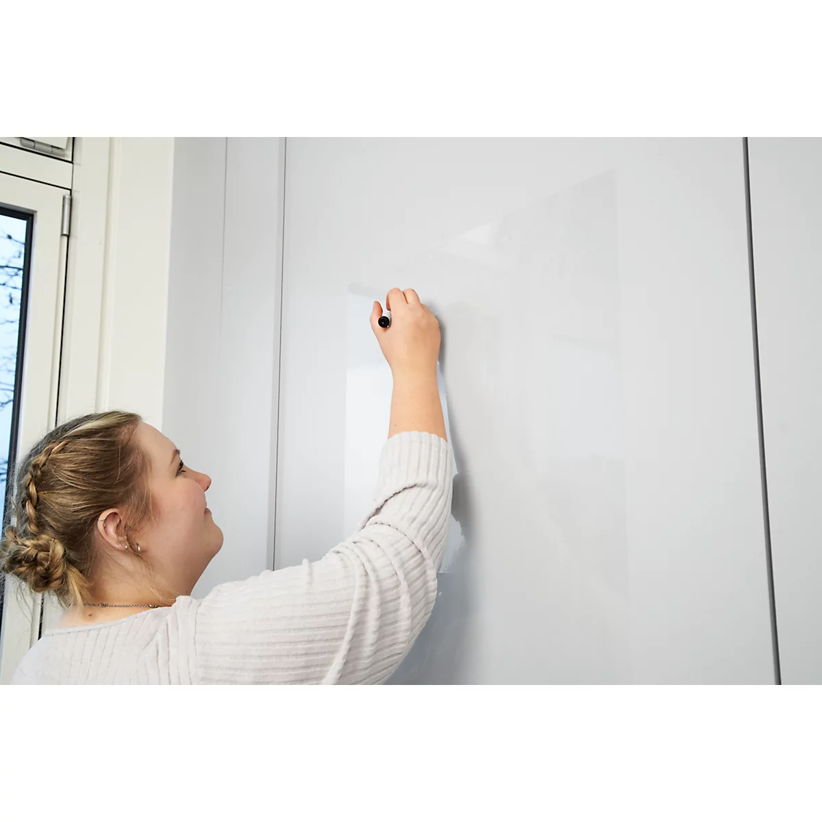 Een vrouw schrijft met een zwarte pen op een wit oppervlak.