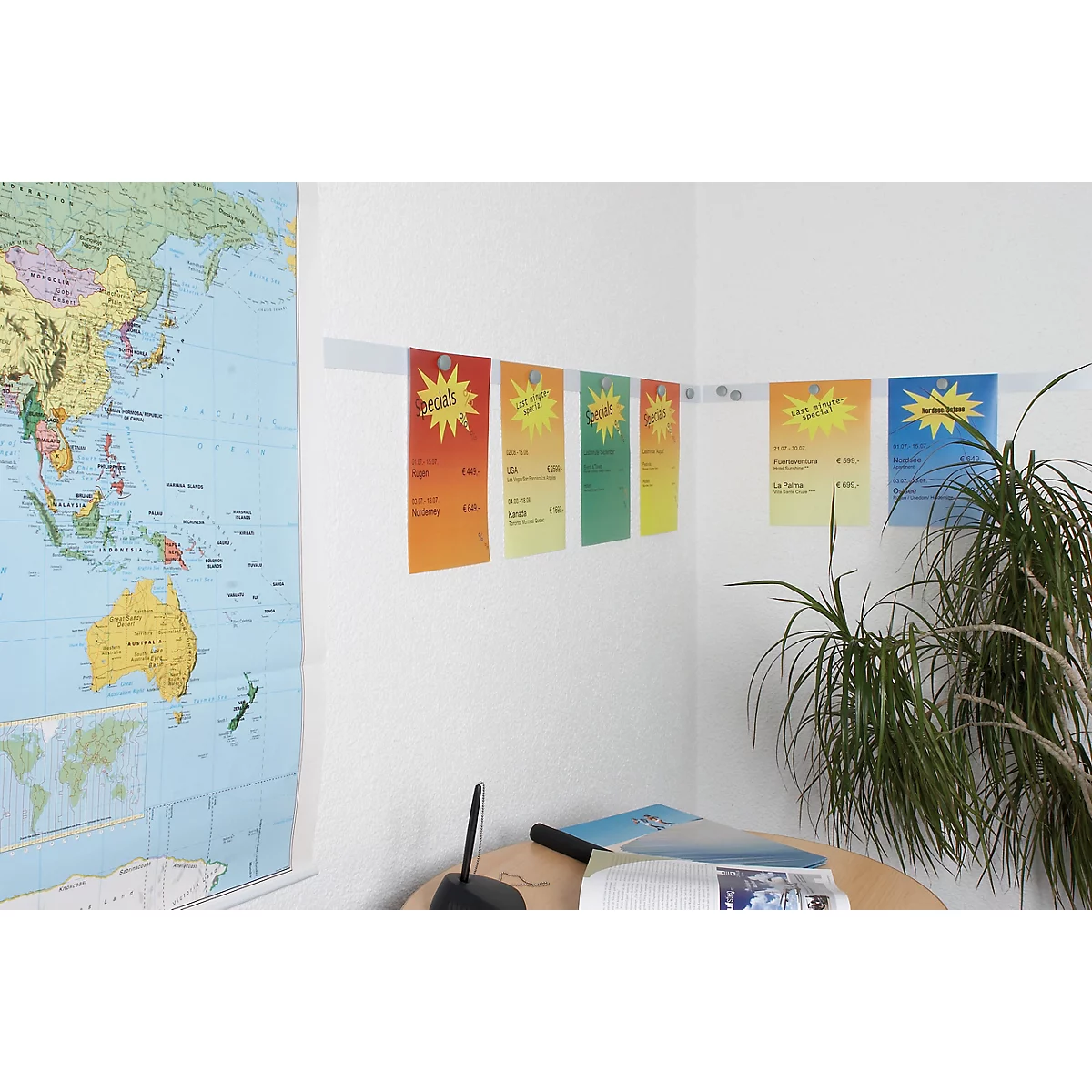 Colorful notes with text hang on a wall, above a world map and a desk.