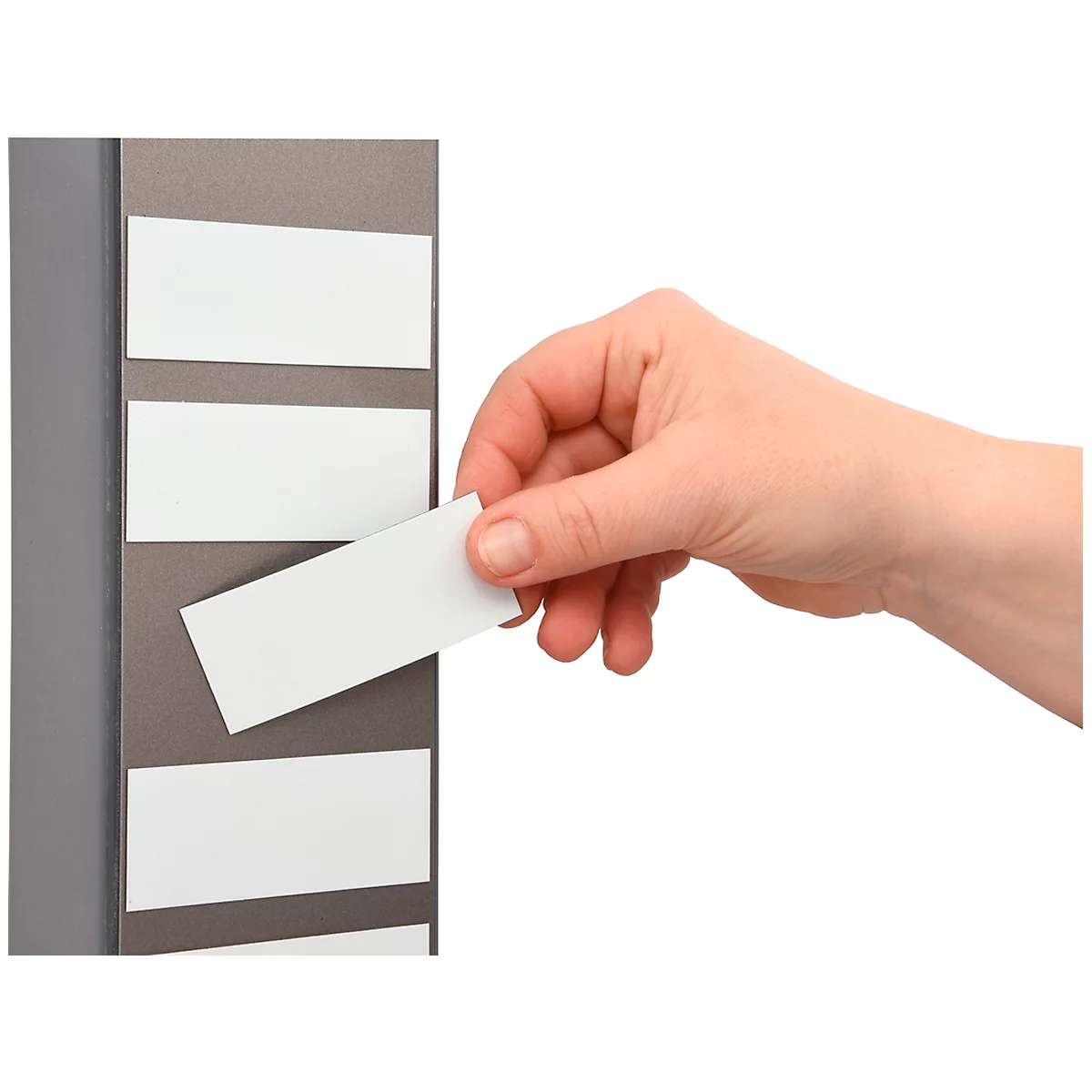 A hand inserts a white card into a card holder. The holder is gray.