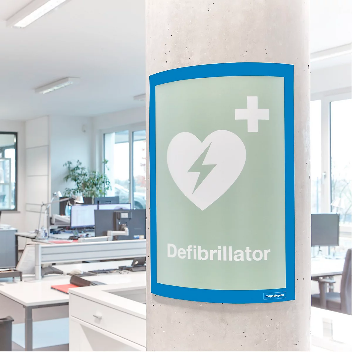 Ein selbstklebender Defibrillator-Hinweisschild auf einer Bürosäule mit Textbeschreibung der Oberflächenhaftung.