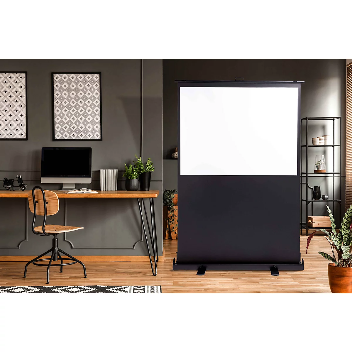 Eine ausziehbare Beamer-Leinwand steht in einem modernen, in Grautönen gehaltenen Büro mit Schreibtisch.