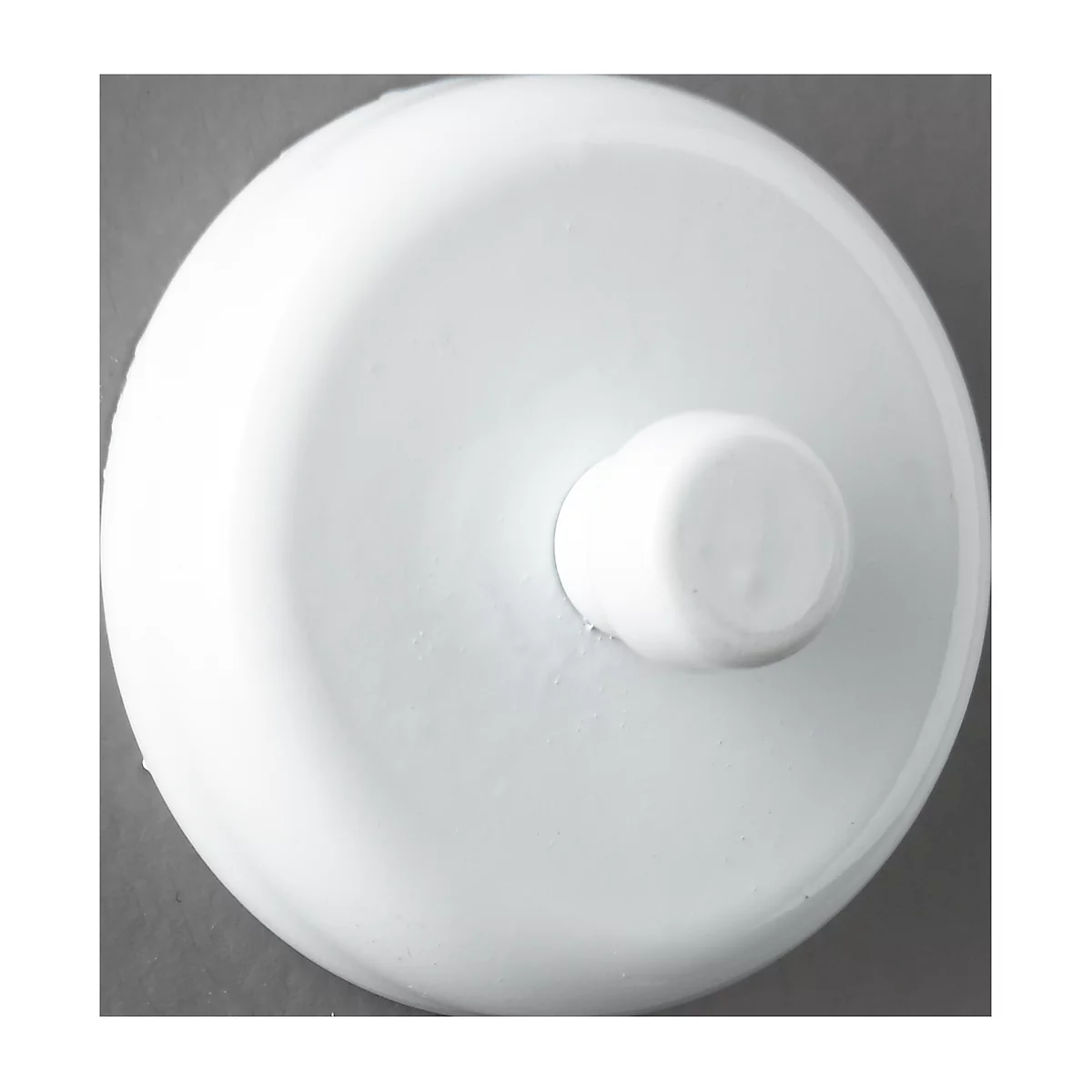 Close-up of a white, circular object with a raised central portion on a gray background.