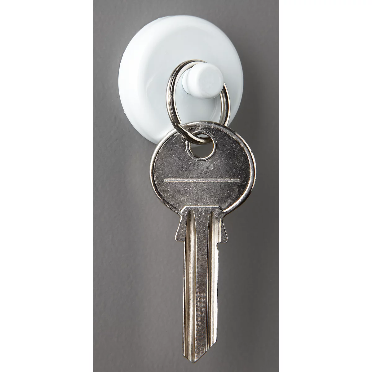 A white key holder with a key. The key is hanging on the holder.
