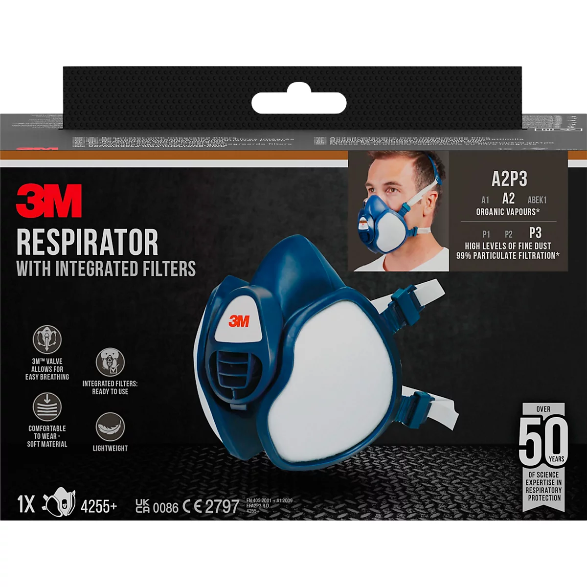 Respirateur 3M bleu et blanc sur l'emballage du produit, un homme avec un masque à droite. Inscription : Respirateur avec filtres intégrés.