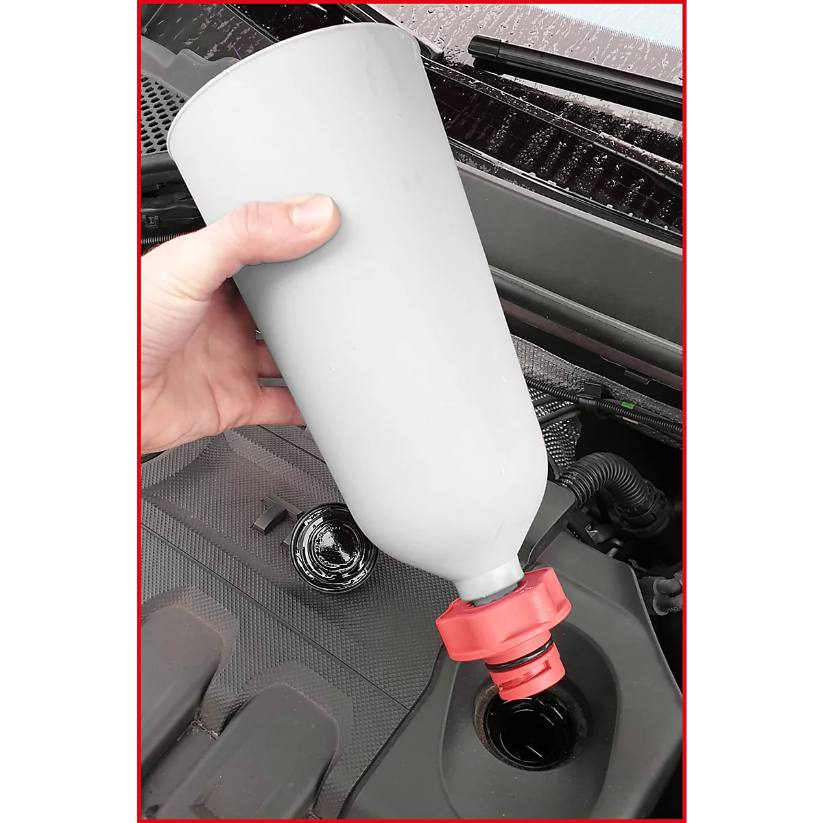 Person befüllt mit einem Trichter Öl in einen Motor.