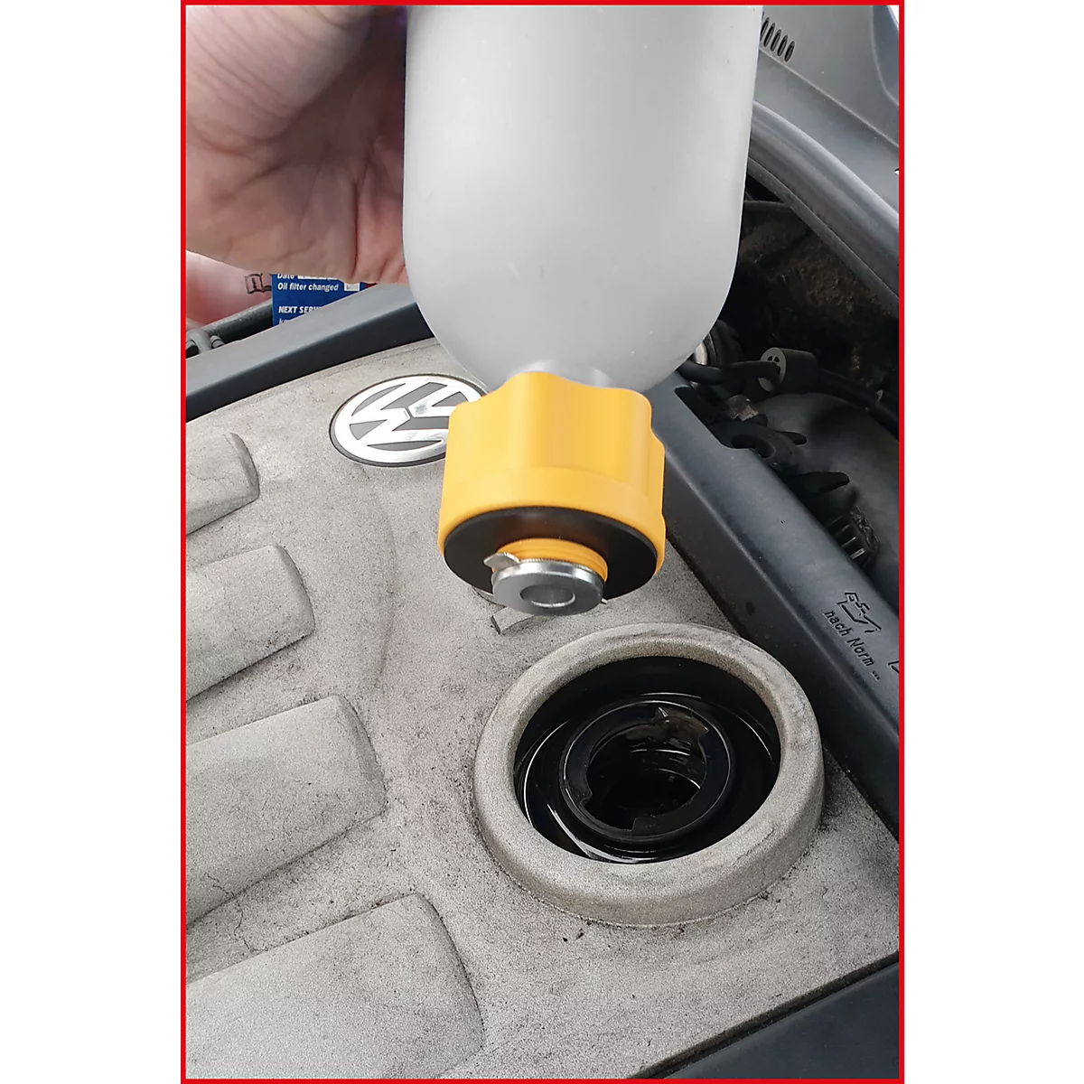 Gelbe Einfüllhilfe für Öl in einem Motorraum. VW-Logo zu sehen.