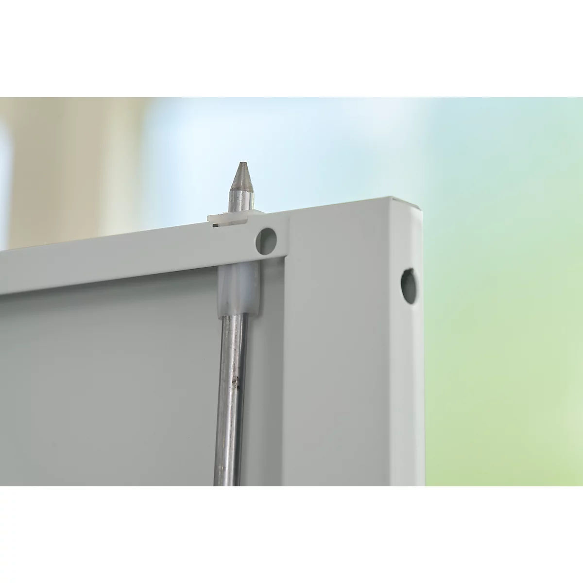 Detailopname van een metalen constructie: een zilveren pin steekt uit een wit frame.