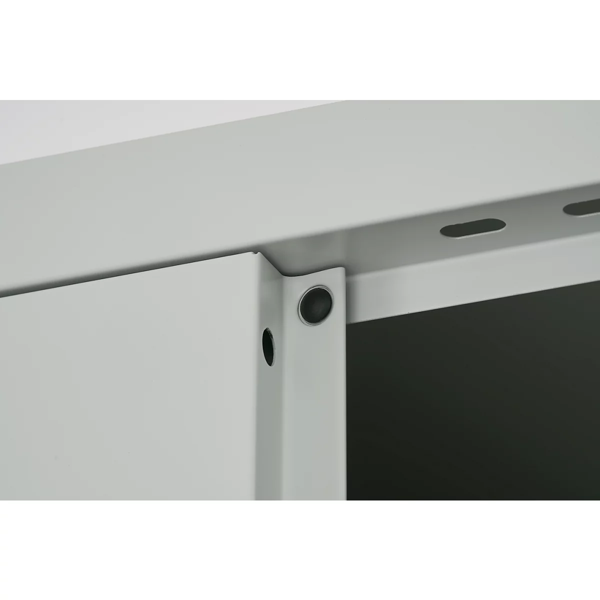 Close-up van een grijze metalen constructie met zwarte klinknagels en een gatenpatroon.