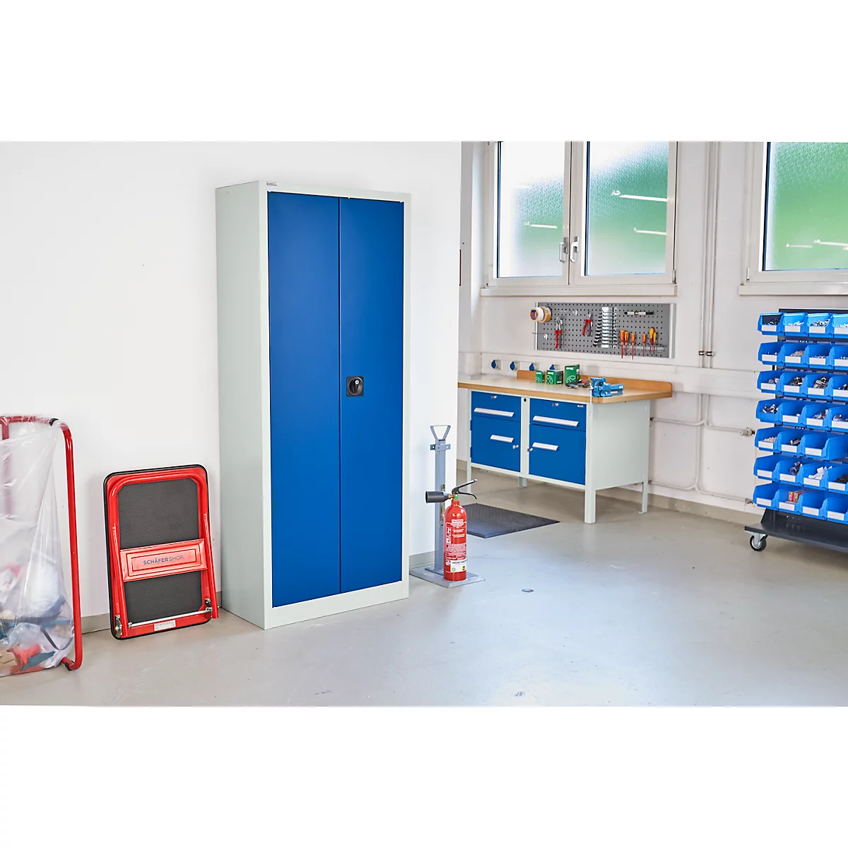Blau metalen kast in een werkplaats. Gereedschap en blauwe lades op de achtergrond.