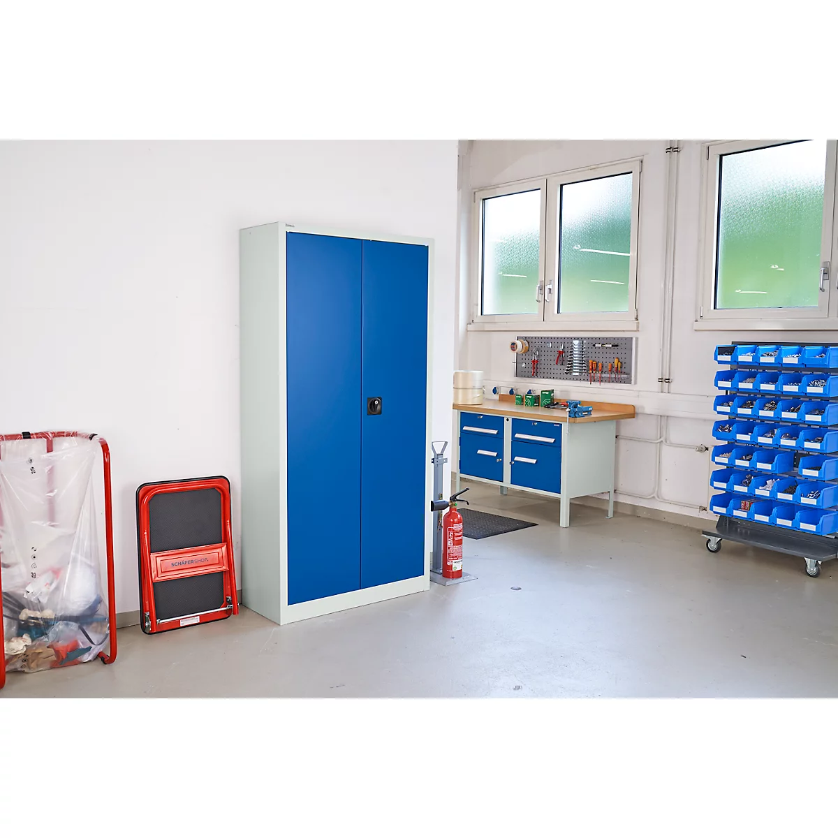 Werkplaats met blauwe kasten en gereedschap. Een brandblusser en een ladder staan ernaast. Lichte omgeving.